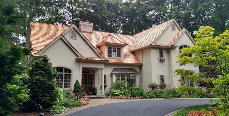 Stucco home with a finished cedar shake roof seen from the street