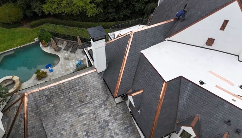 Copper valley and sidewall flashing meeting a low-slope membrane section beside the pool