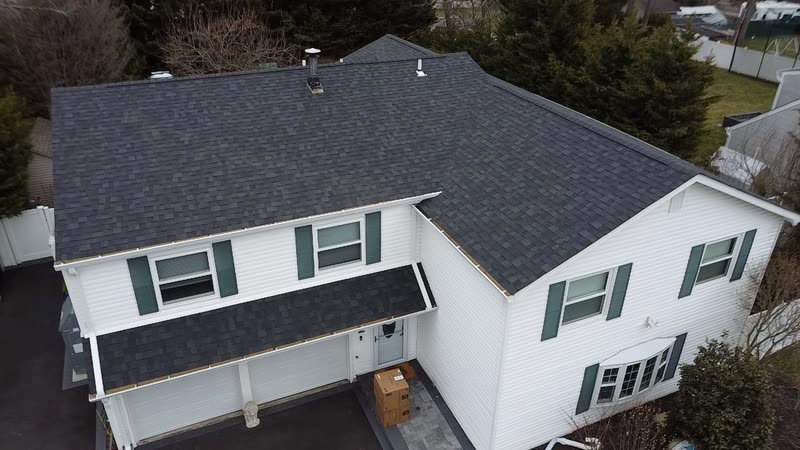 Completed dark shingle roof on a white home, front elevation from above