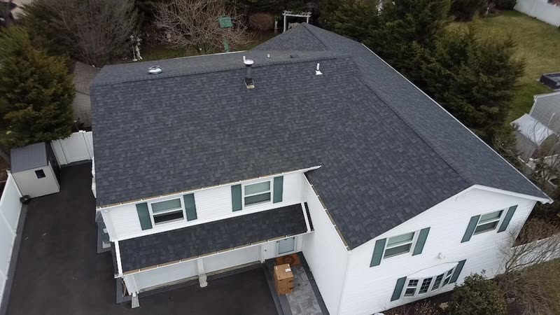 White home with green shutters and a newly installed dark shingle roof