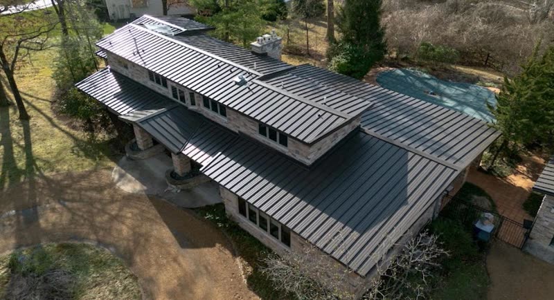 Dark standing seam metal roof running the full length of a low-pitched contemporary house